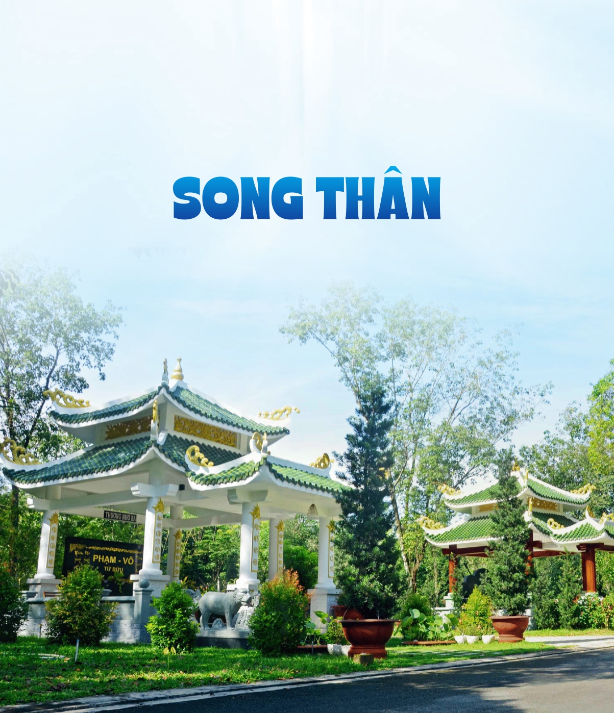 spacious family tomb area with twin monuments under a large willow tree in a sun-dappled park